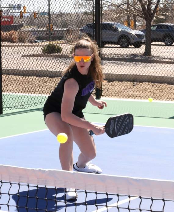 a woman playing pickleball outside hitting a shot during a lesson.